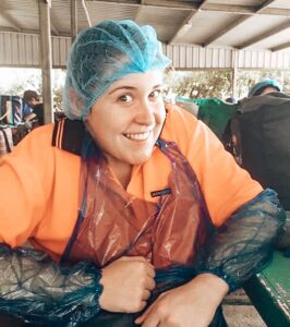 88 days of farm work – Girl smiling at camera with hair net and plastic apron and arm protectors on 88 days of farm work - Girl smiling at camera with hair net and plastic apron and arm protectors on