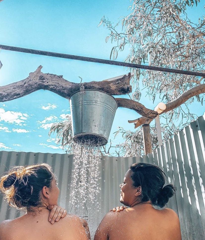 Our favourite camps found through these apps Two girls showering outside under a bucket shower